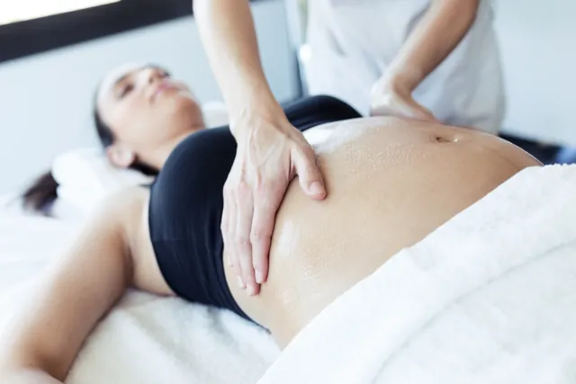 Séance d'ostéopathie douce sur le ventre d'une femme enceinte