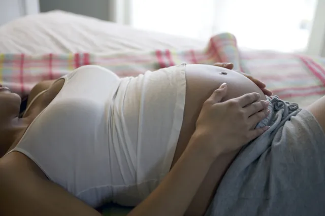 Femme enceinte allongée, la main posée sur son ventre