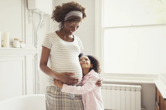 Petite fille qui serre dans ses bras sa maman enceinte
