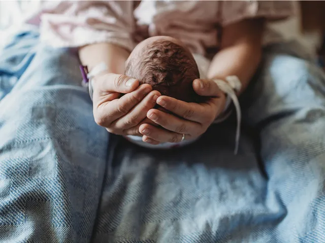 Tête d'un nouveau-né tenue délicatement dans les mains